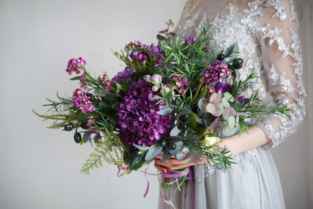 A wedding bouquet of purple hydrangeas olive branches and succulents