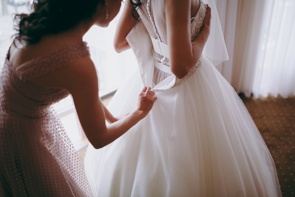 Maid of honor helping the bride with her dress