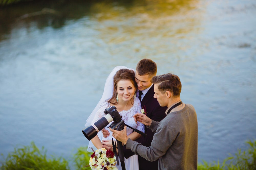 Photographer showing the bride and groom his photos