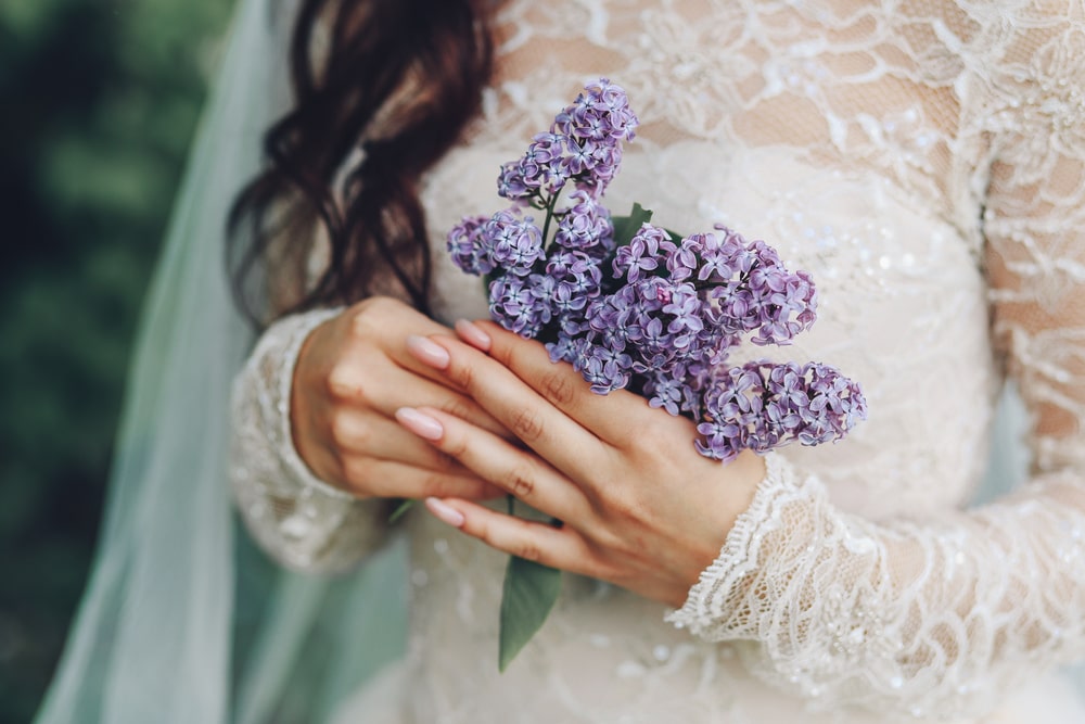 Woman in wedding dress holding a bouquet of lilacs