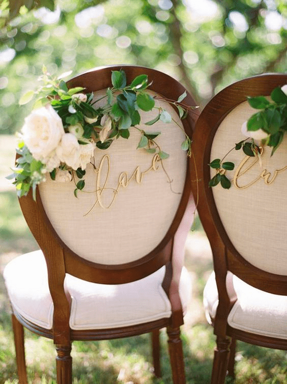 Bride and groom chair decorated with flowers and sign
