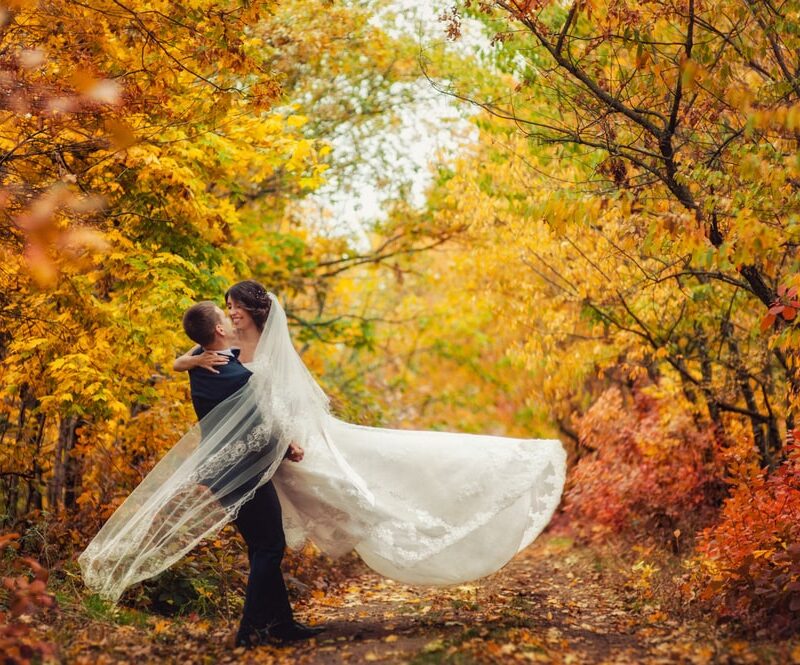 Happy young newly married wedding couple on a walk in golden yellow fall autumn park around trees