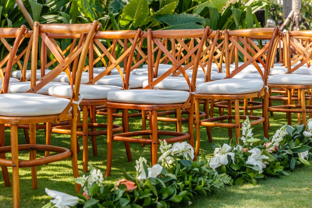 Wedding chairs with white cushions and floral decoration with white Lily flowers