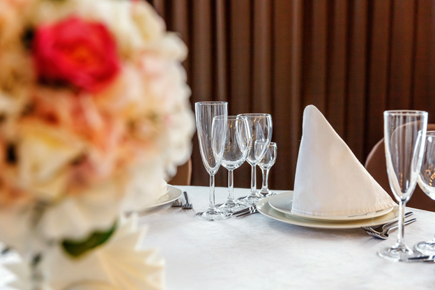 Glasses, flowers, fork, knife, napkin folded in a pyramid