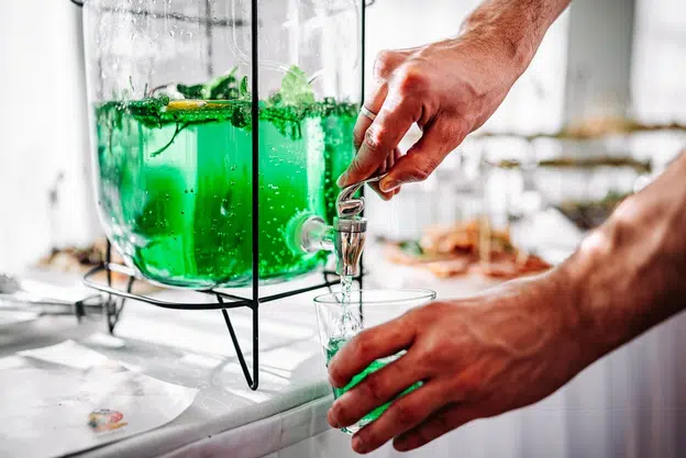 Man pours colored lemonade from a bottle into a glass