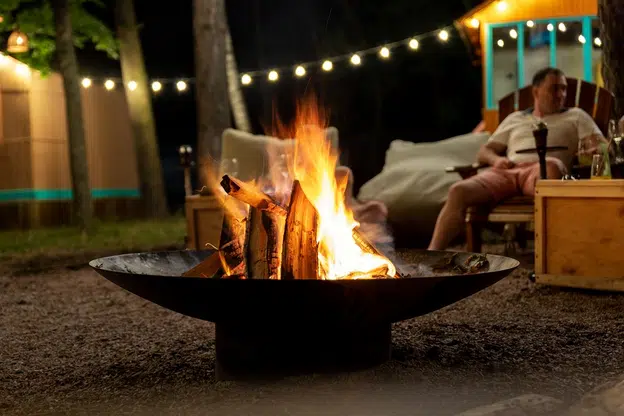 Man sitting next to fire outside at night