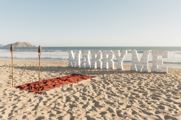 Marriage proposal with red carpet on the sand and torches