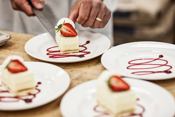 Chef hands placing a layered desert on a plate, presentation of a sweet dish