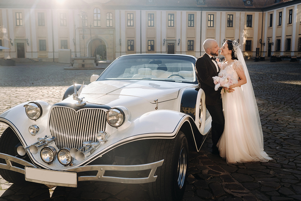 Elegant wedding couple In the courtyard of the castle near a retro car.