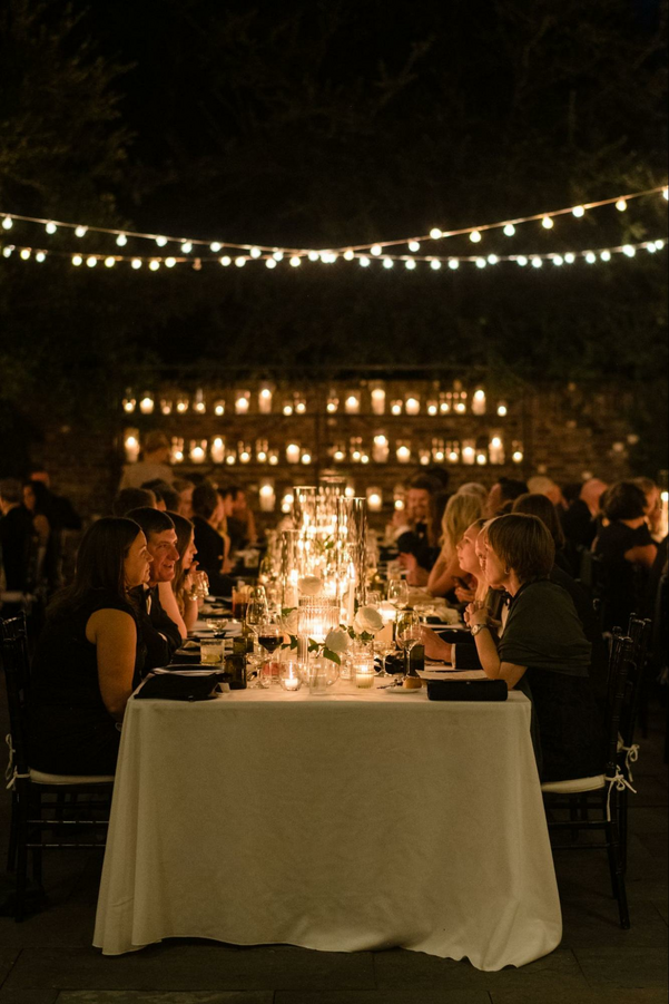 Elegant Outdoor Wedding Lighting Setting and Table Spread with Wedding Guests.