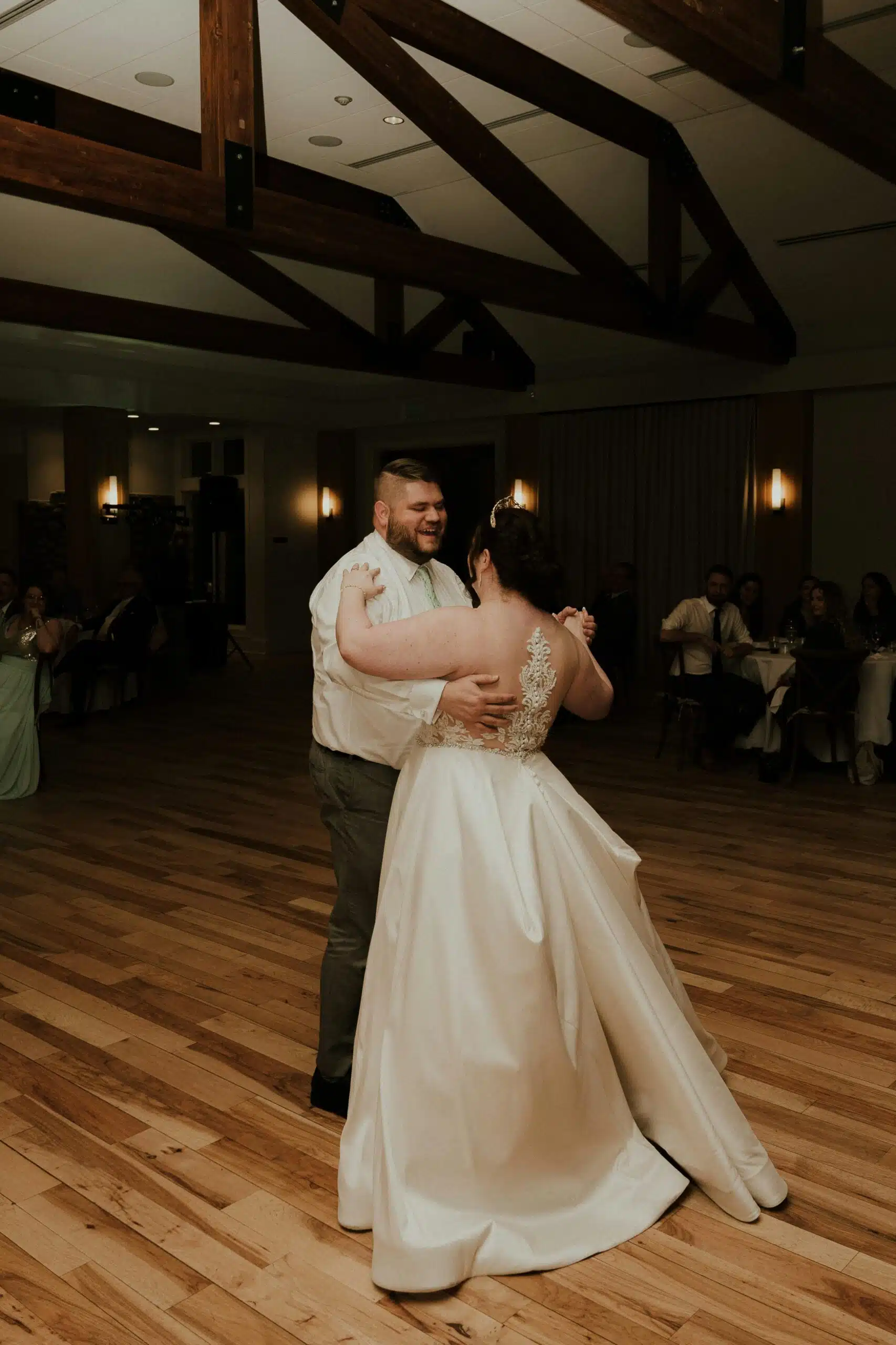 A newlywed couple sharing their first dance on a themed wooden dance floor, emphasizing the charm of renting a quality dance floor.