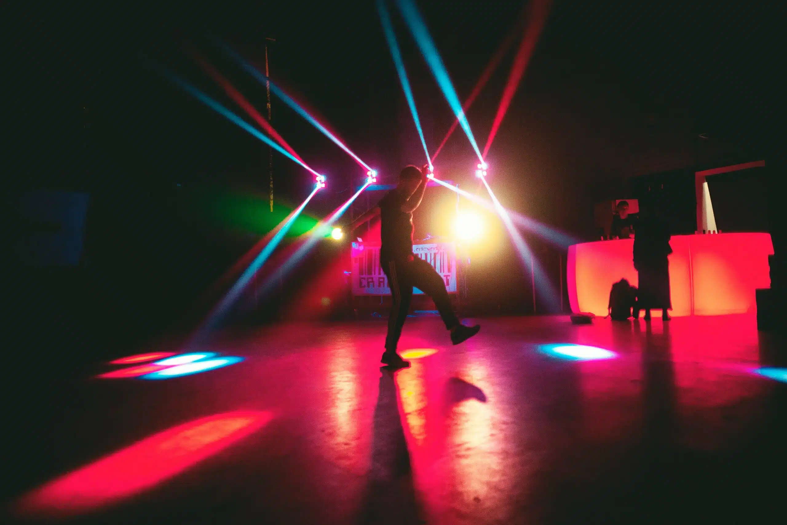 A DJ-lit indoor dance floor with vibrant lights, perfect for parties and corporate events, illustrating the energy of dance floor rentals.