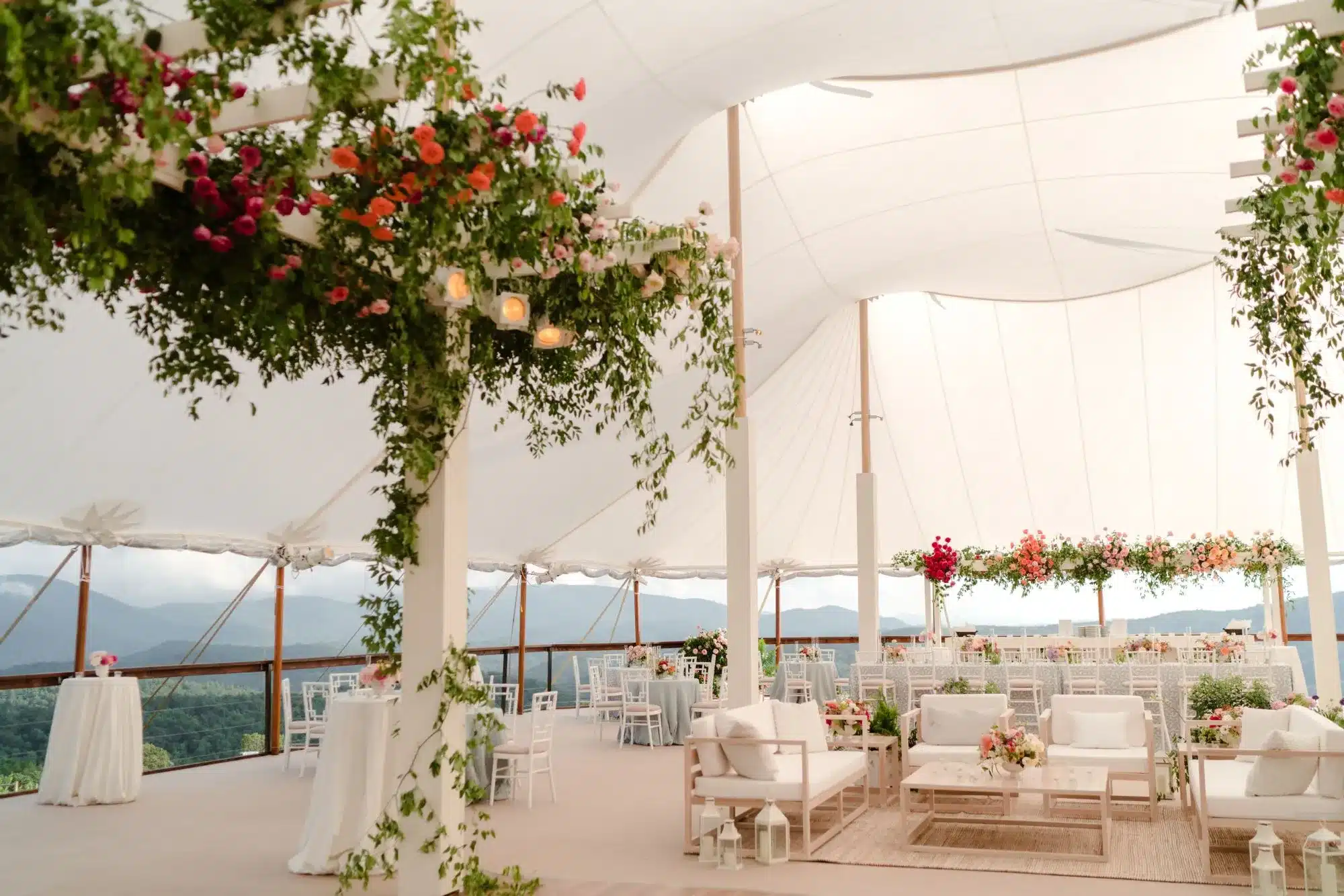 Upscale sailcloth tent with floral ceiling installs, cozy lounge vignettes, and scenic views.