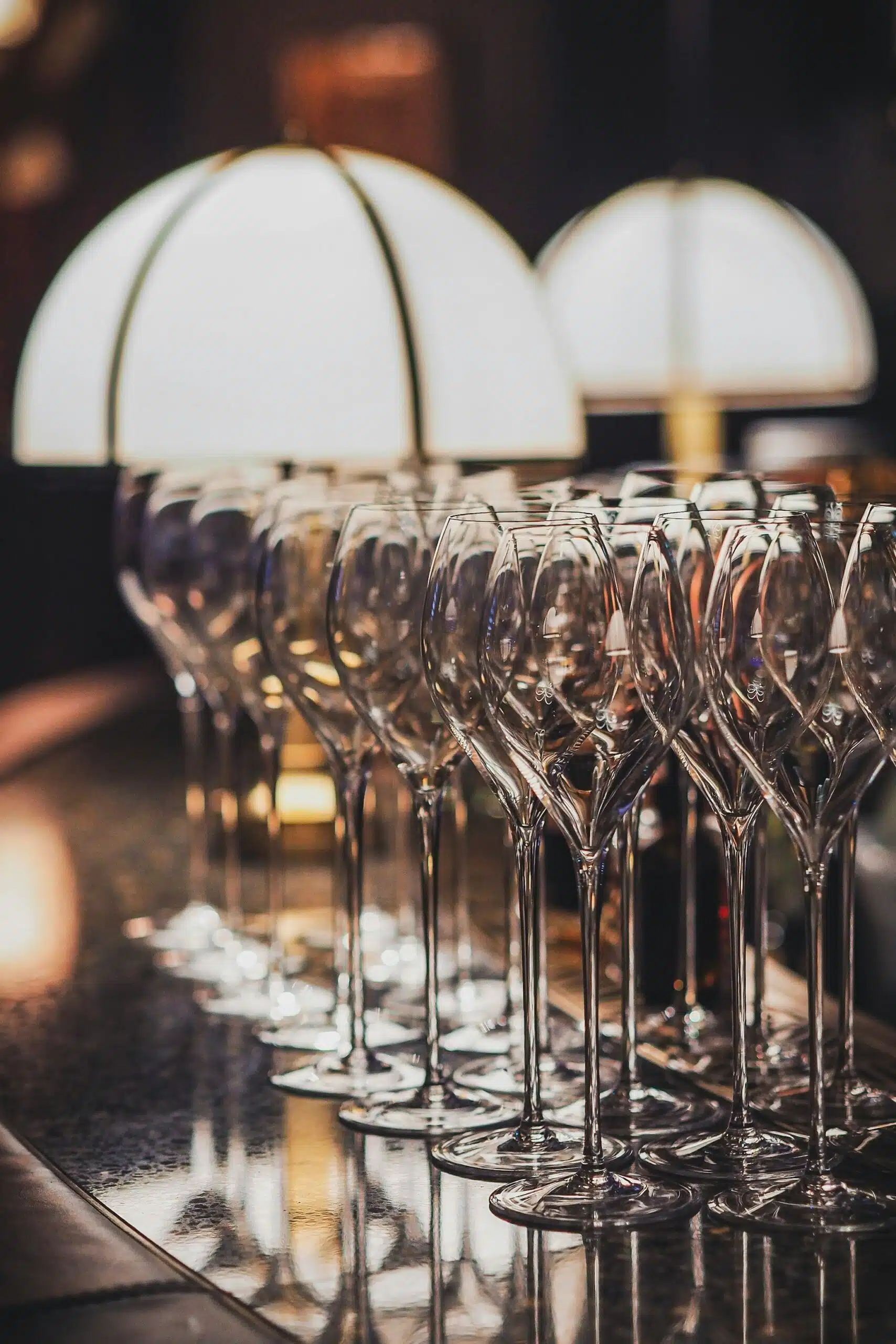 A lineup of elegant customized wine glasses arranged under soft ambient lighting, showcasing how coordinated glassware accents elevate the wedding&rsquo;s overall aesthetic.