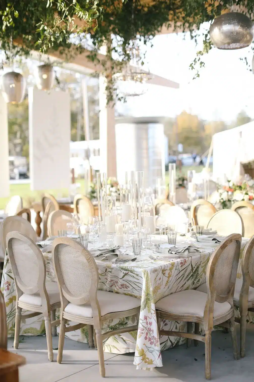 Outdoor reception table with botanical print linens and ivory upholstered chairs. | Curated Events Outdoor reception table with botanical print linens and ivory upholstered chairs.