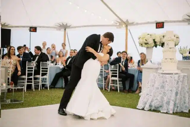 Bride and groom dipping on light wood dance floor under sailcloth tent