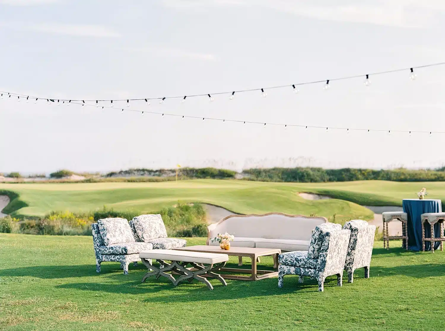 Outdoor lounge setup with patterned chairs, neutral sofas, and string lights