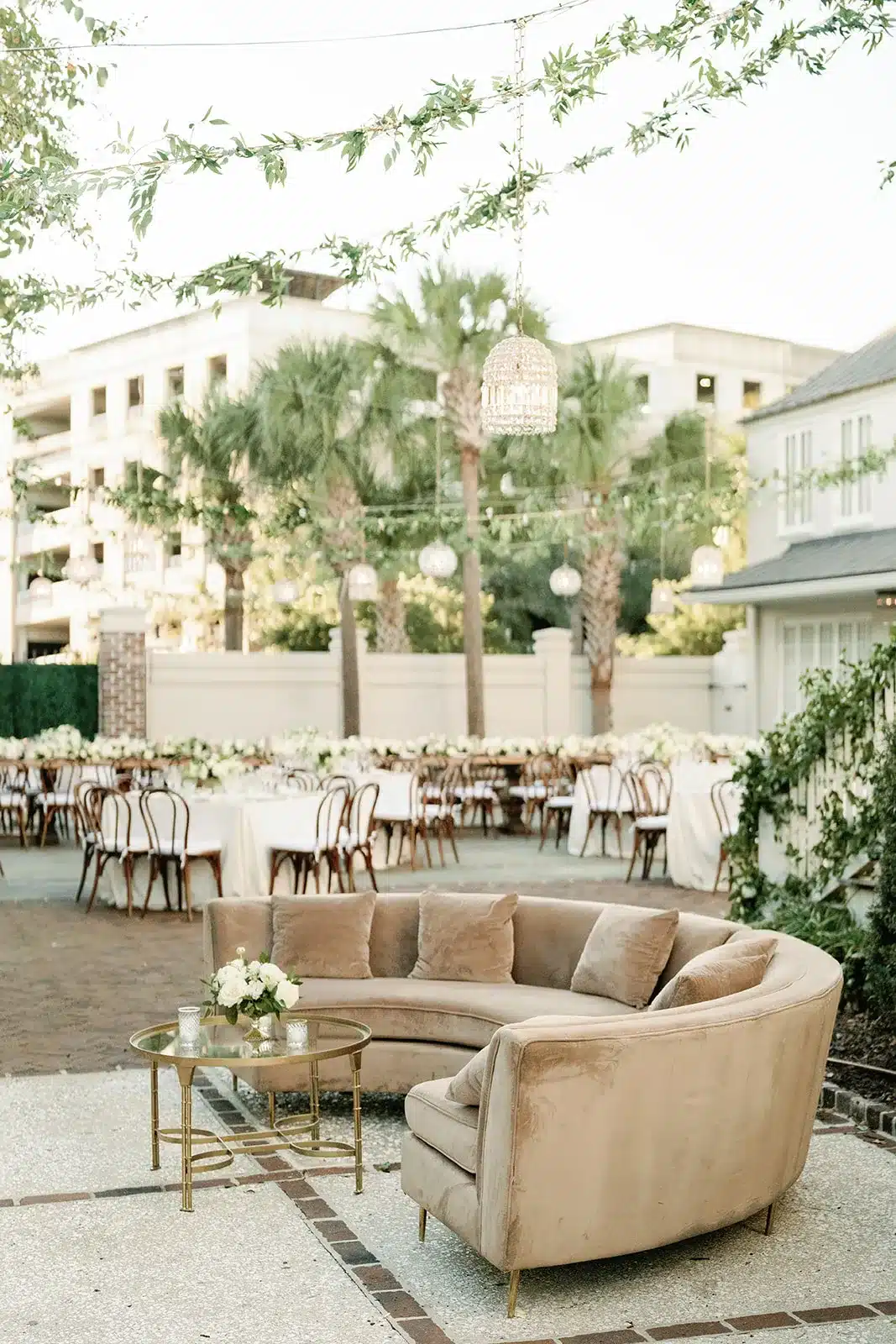 Curved beige sofa with outdoor wedding reception tables in background | Curated Events Curved beige sofa with outdoor wedding reception tables in background