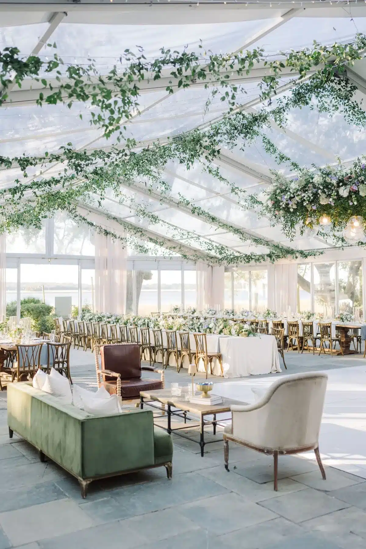 Clear wedding tent with greenery ceiling décor and lounge seating