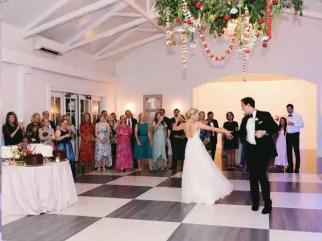 Wedding reception on wood grain patterned dance floor with hanging florals