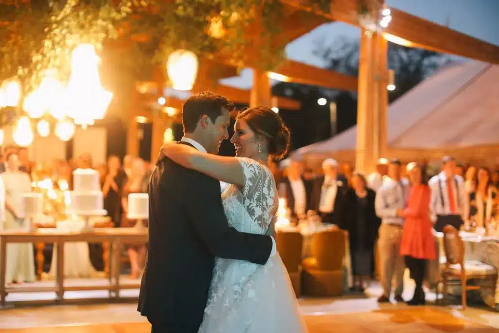 Bride and groom sharing their first dance under glowing chandeliers