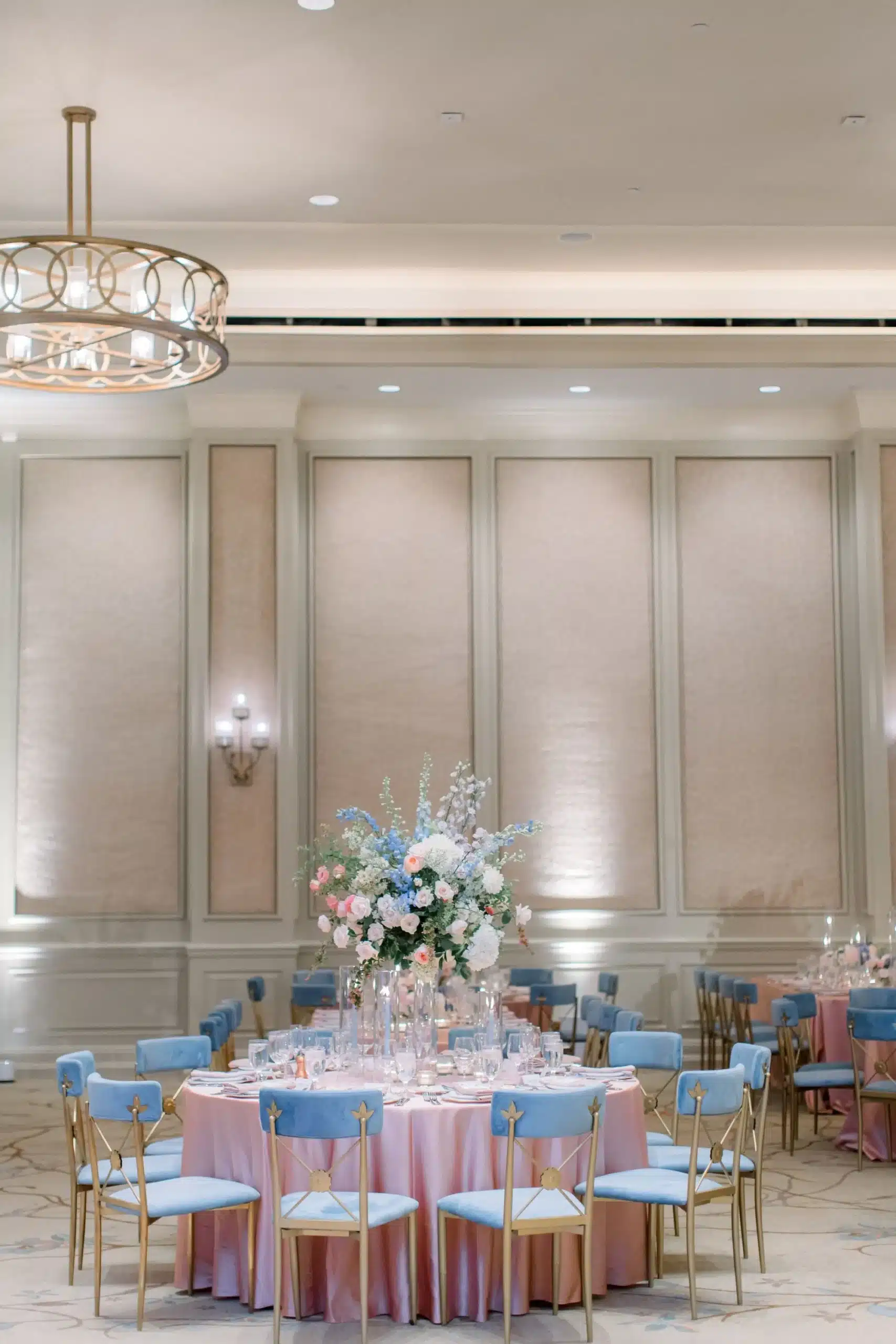 Ballroom wedding reception with pastel floral centerpiece and soft pink table linens