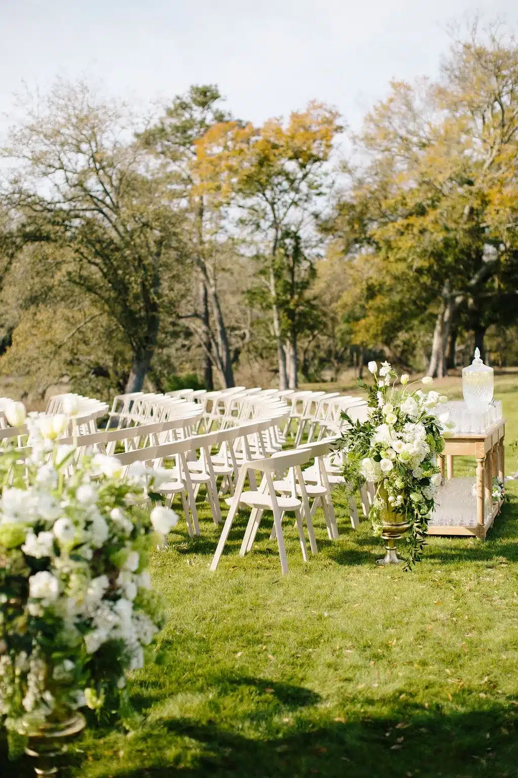 Outdoor wedding ceremony chairs with white floral arrangements. | Curated Events Outdoor wedding ceremony chairs with white floral arrangements.