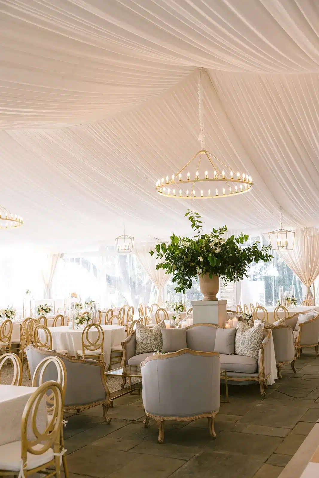 Elegant tent interior with lounge seating, round tables, and neutral-toned d&eacute;cor.