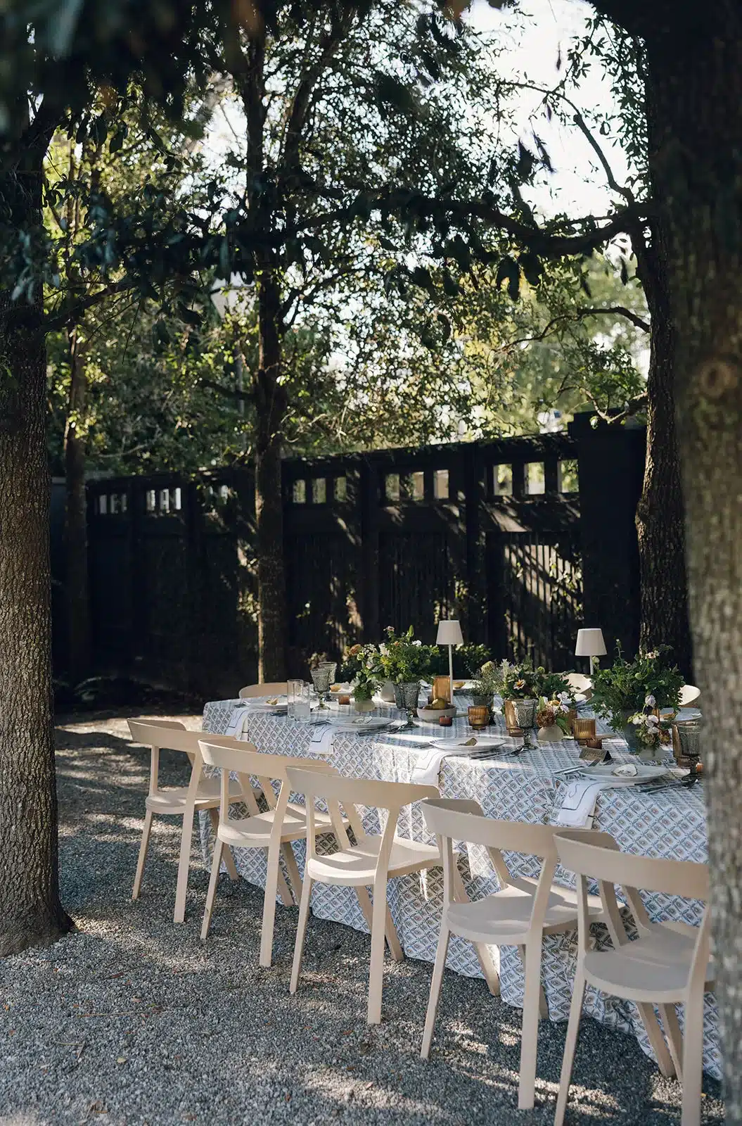 Long dining table set for a holiday event under trees. | Curated Events Long dining table set for a holiday event under trees.