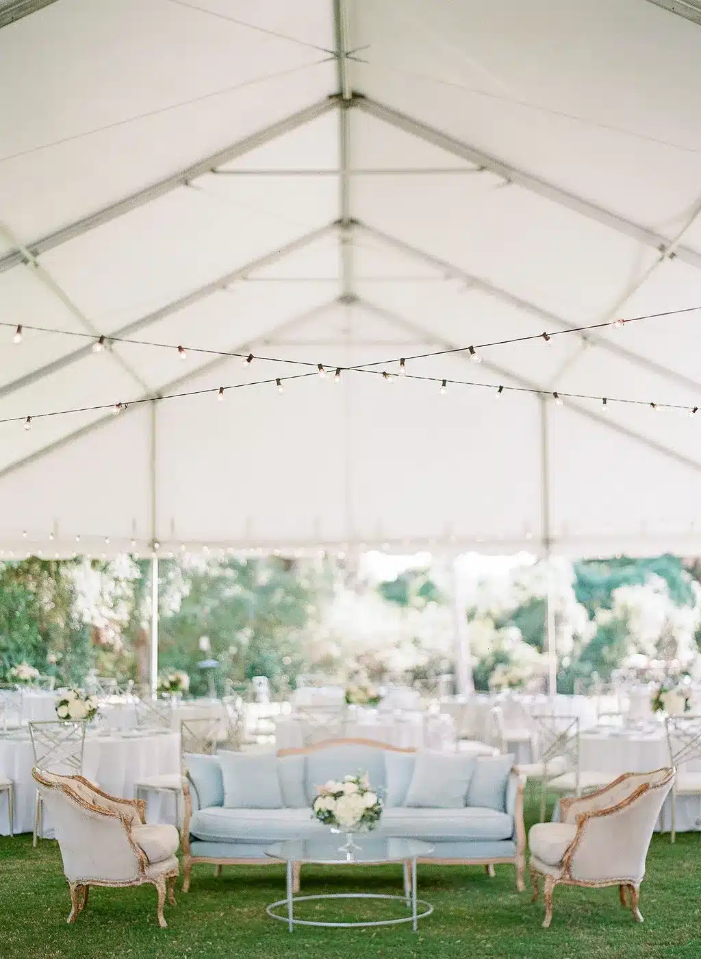 Cozy tent lounge with vintage-style sofas and soft greenery for holiday gatherings.