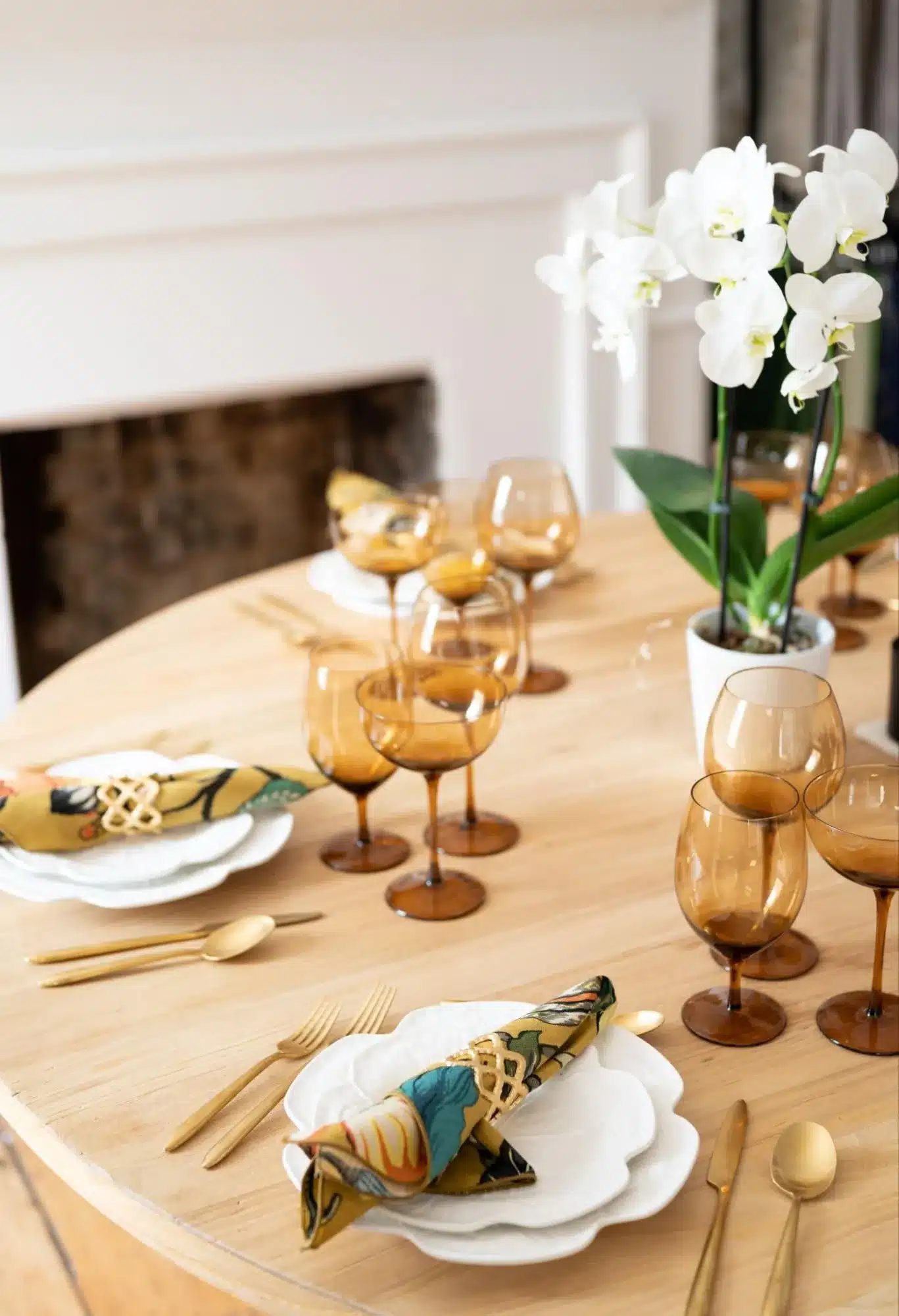 Modern round table with amber glassware and patterned napkins for a festive dinner
