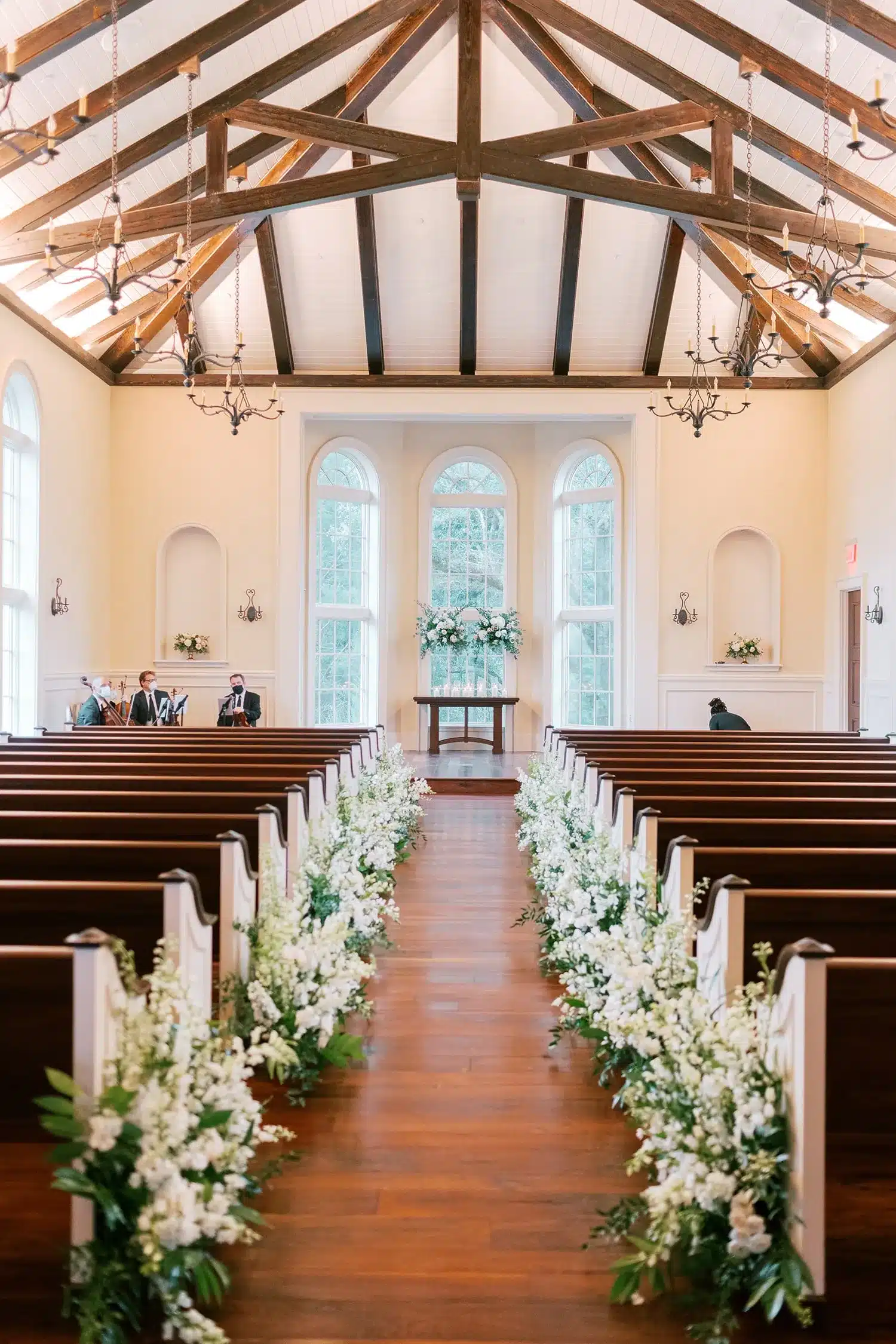 Wedding chapel aisle lined with white floral arrangements. | Curated Events Wedding chapel aisle lined with white floral arrangements.