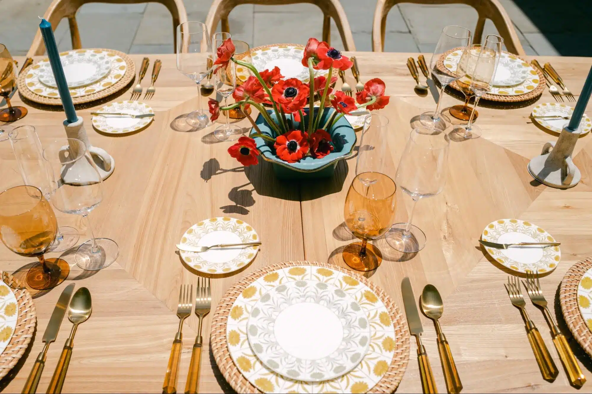 Bright holiday table featuring red floral centerpiece and gold-accented tableware.