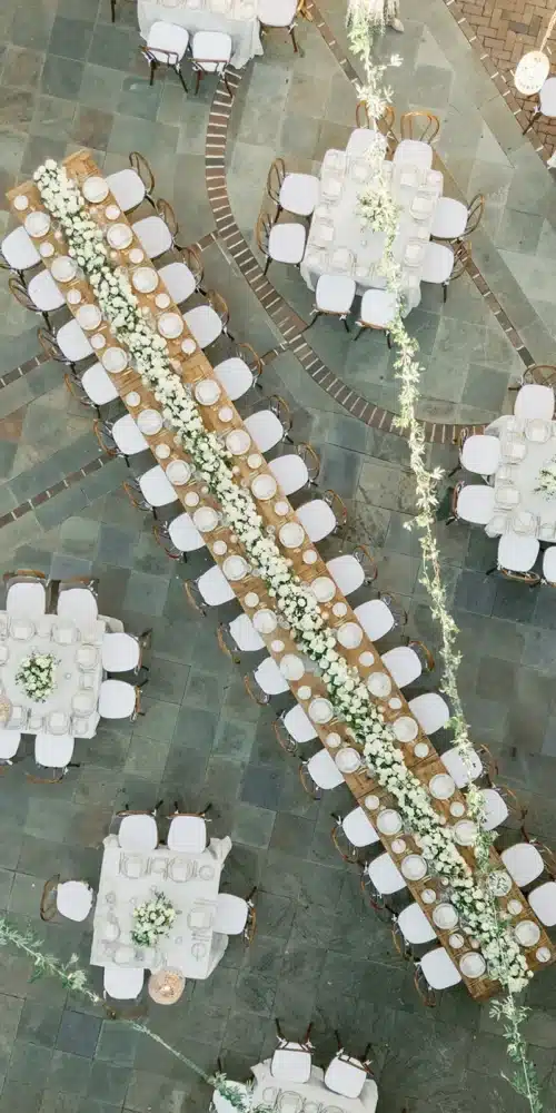 Aerial view of elegant wedding table arrangements featuring long and round tables with white floral décor.