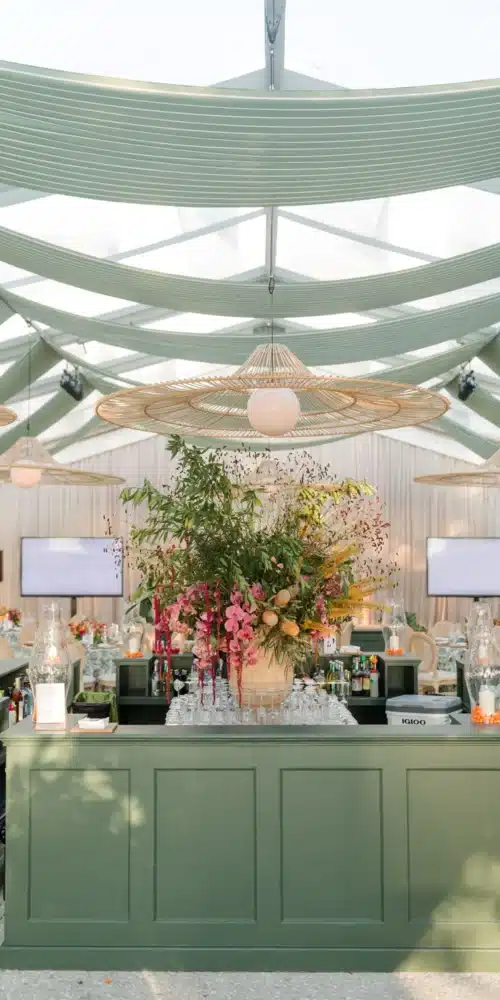 Event bar with floral arrangement under modern hanging lights.