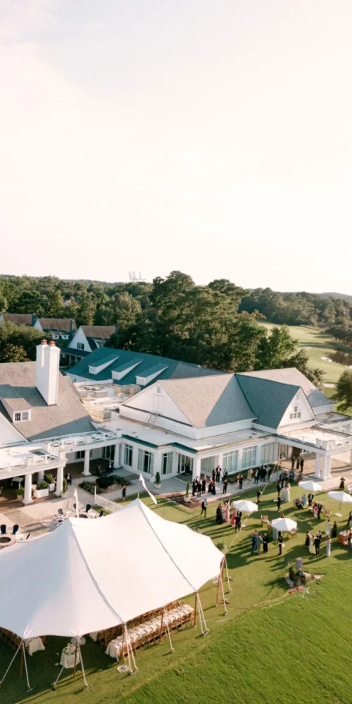 Aerial view of a Charlotte mansion lawn with a white event tent and guests gathered outside.
