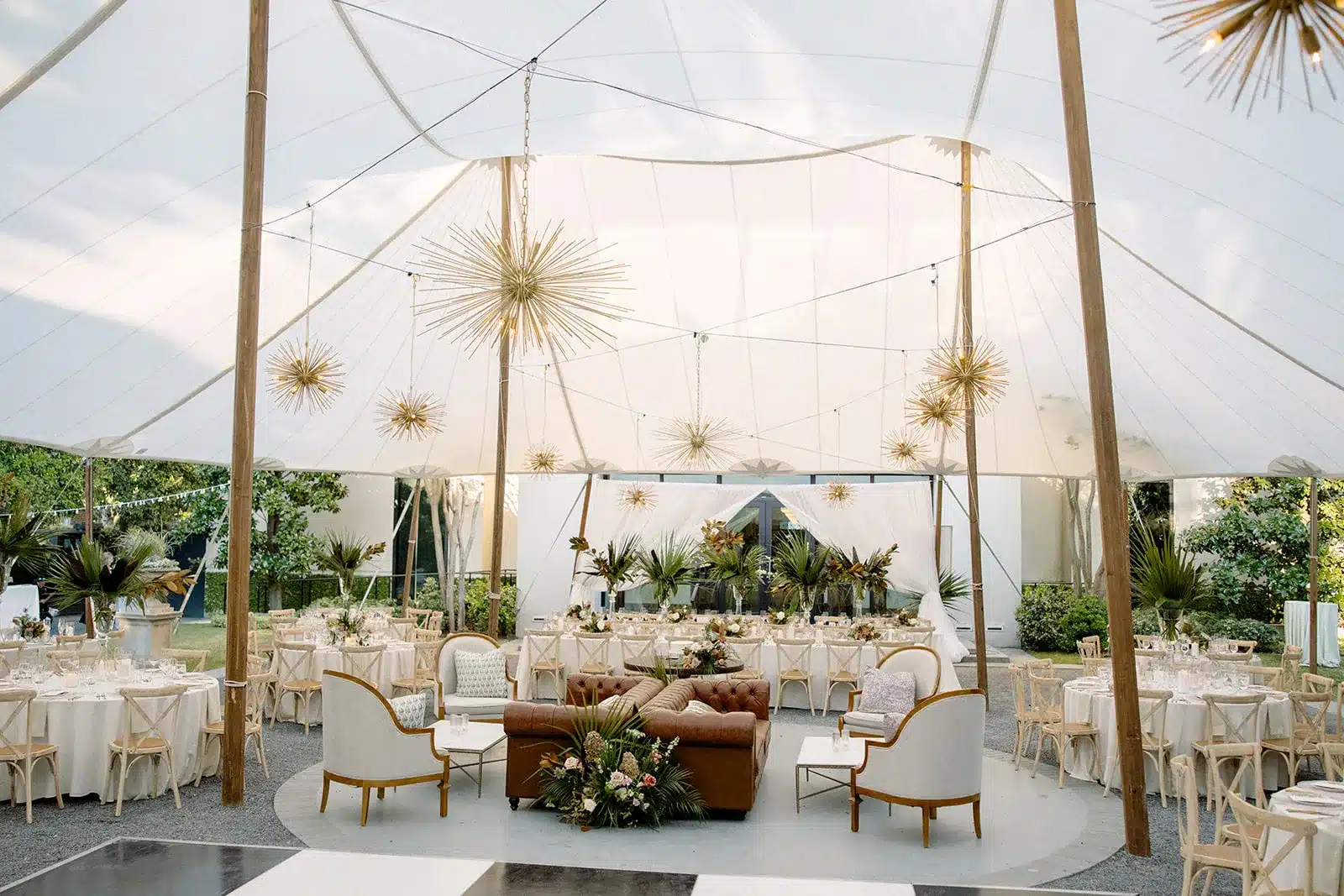 Sailcloth tent reception with lounge seating, round dining tables, and starburst pendant lighting. | Curated Events Sailcloth tent reception with lounge seating, round dining tables, and starburst pendant lighting.