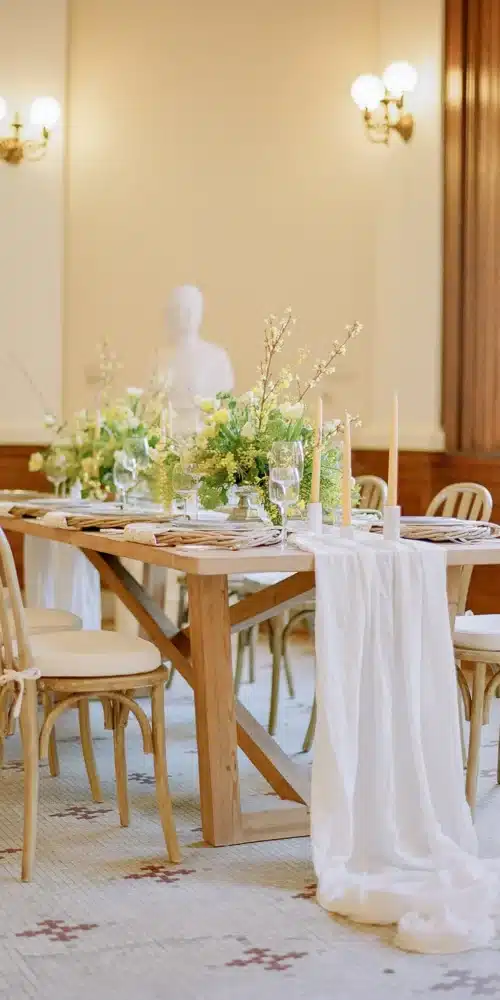 Softly lit indoor reception table with candles and greenery at a historic venue