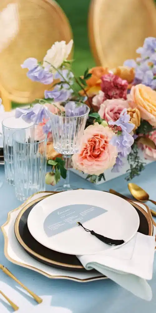 Spring wedding place setting with pastel florals, candles, and gold-rimmed tableware
