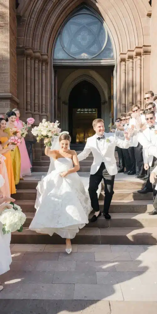 Newlyweds exit a historic church as guests celebrate on the steps