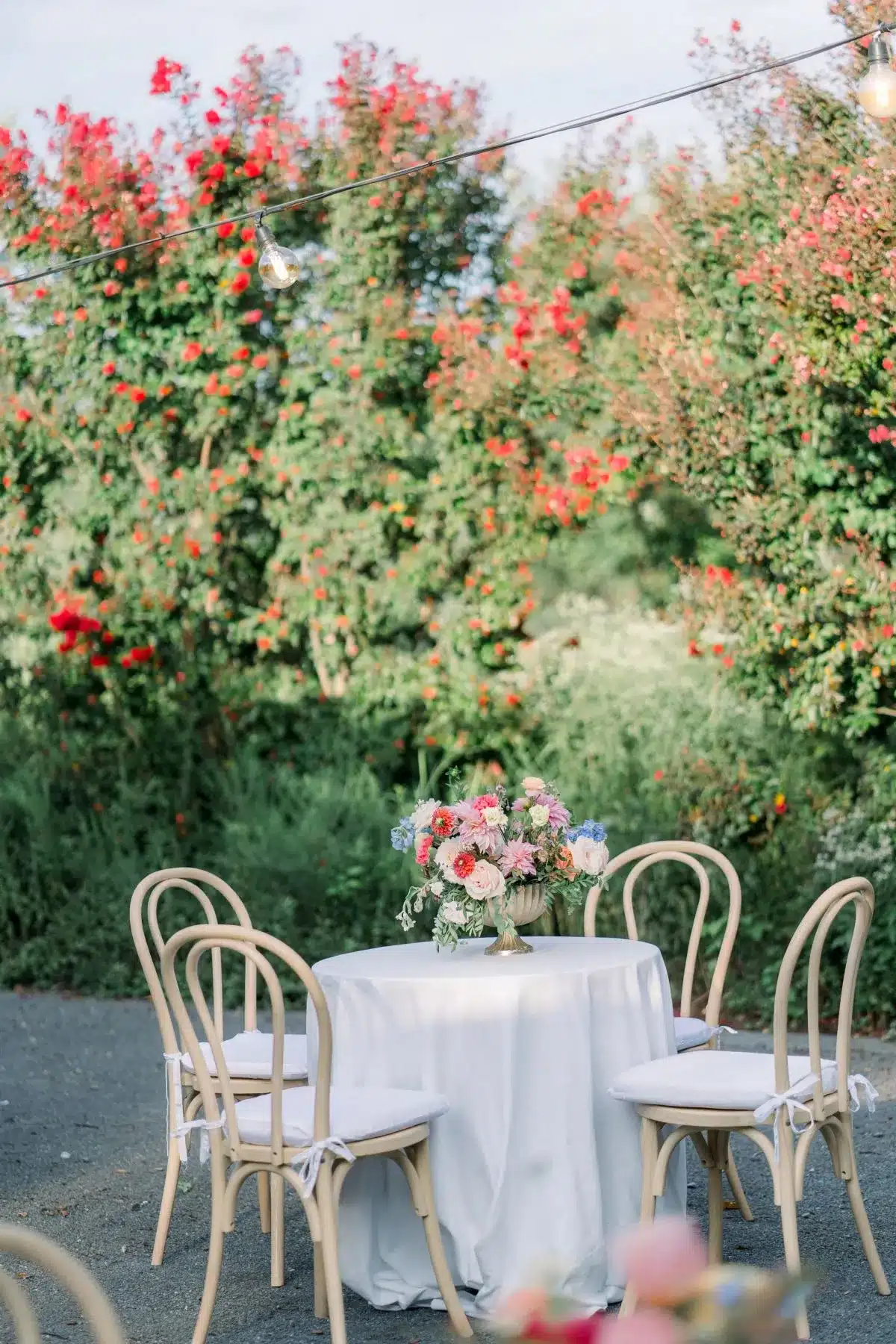 Small outdoor cocktail table with floral centerpiece set in a garden