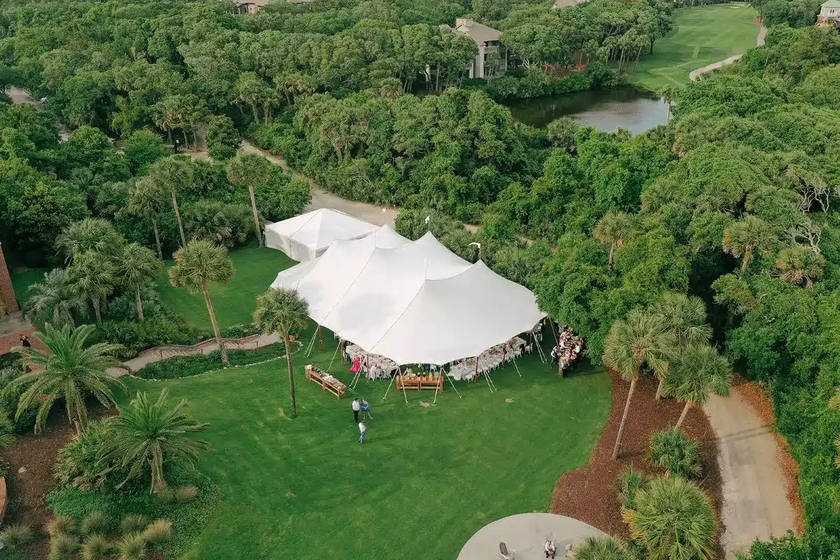 Aerial view of a spacious white event tent set up on a lush green estate for a large gathering.