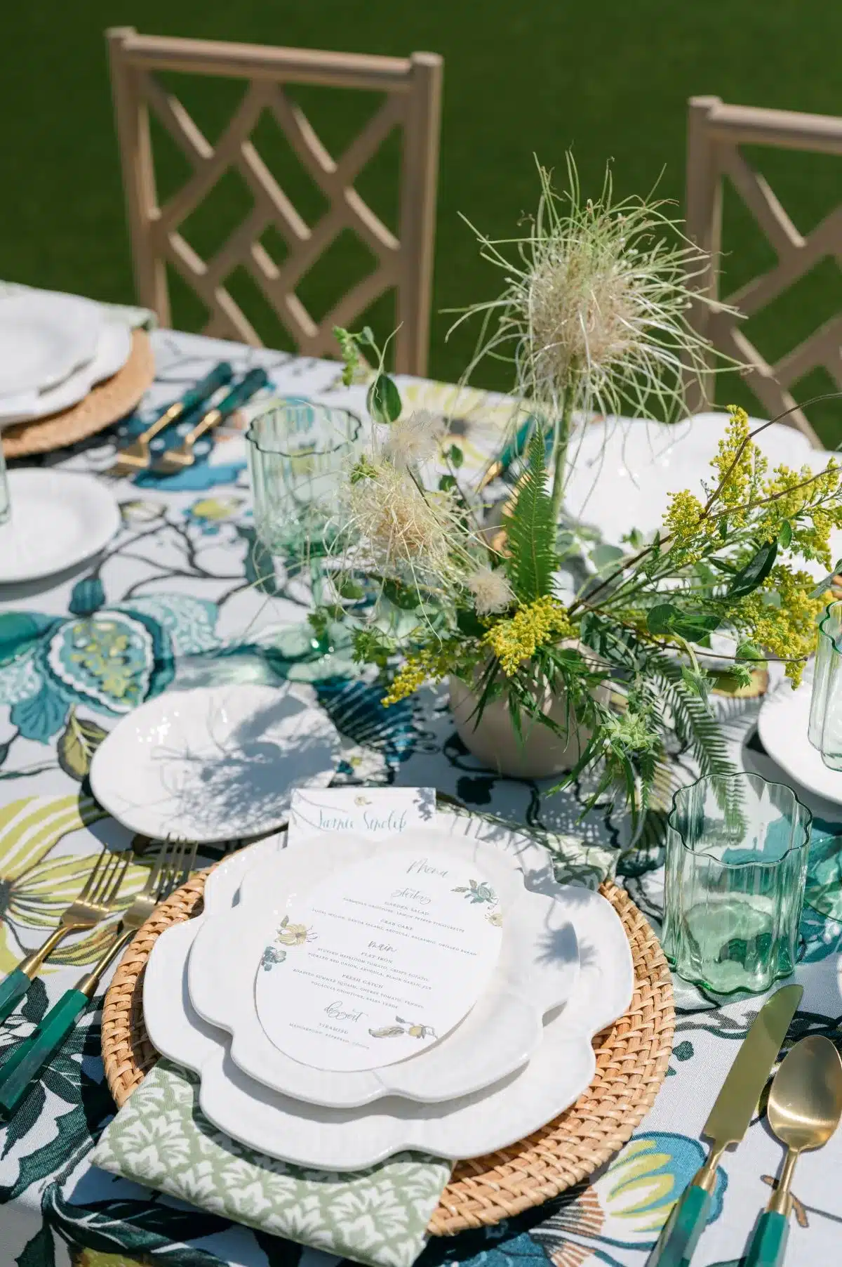 Colorful botanical tablescape with woven chargers, layered plates, and fresh greenery centerpiece.