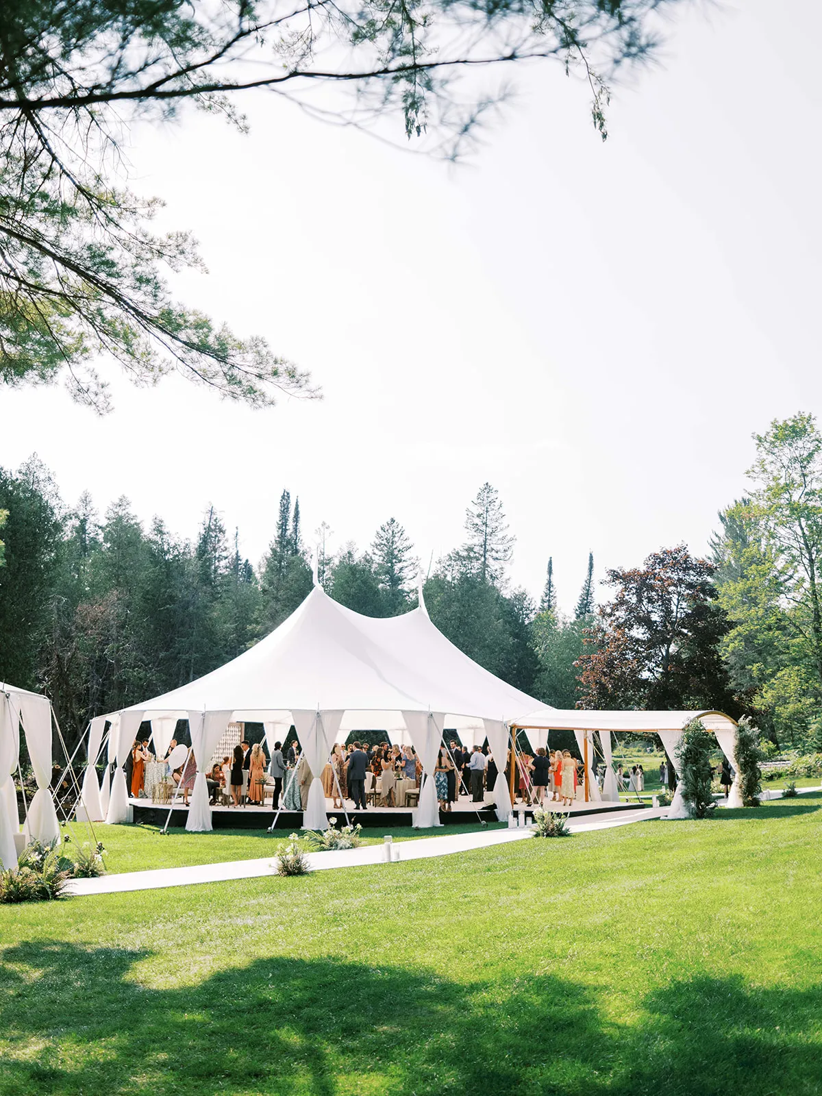 Open-sided sailcloth tent with guests gathered for an outdoor event