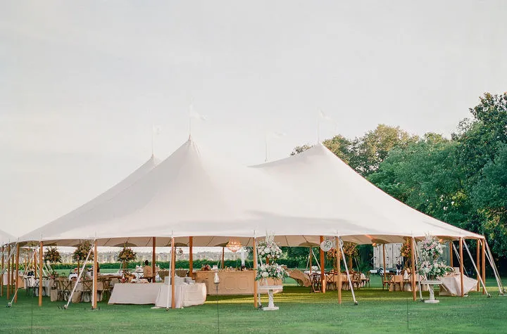 Elegant sailcloth tent with reception tables set on a grassy lawn