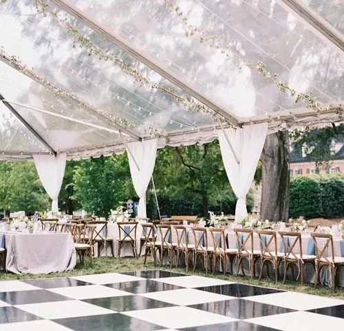 Clear-top tent reception with black-and-white checkered dance floor and long banquet seating