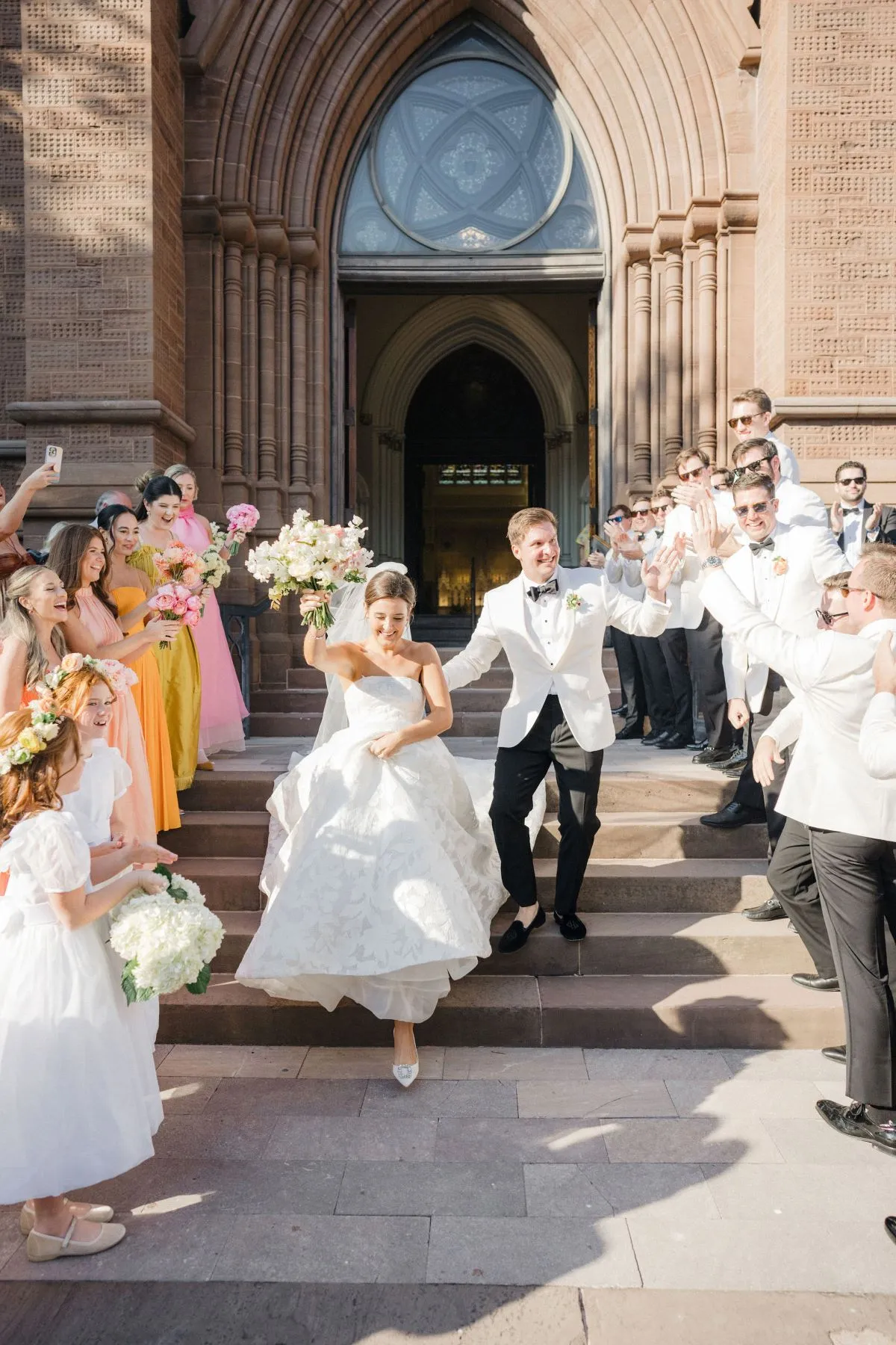 Newlyweds exiting church surrounded by cheering guests and wedding party