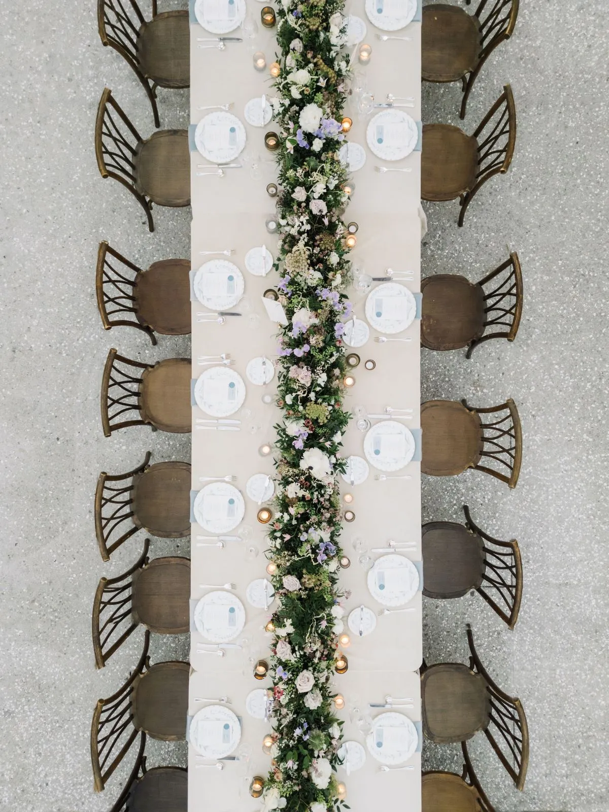 Overhead view of banquet table with greenery runner and wooden chairs