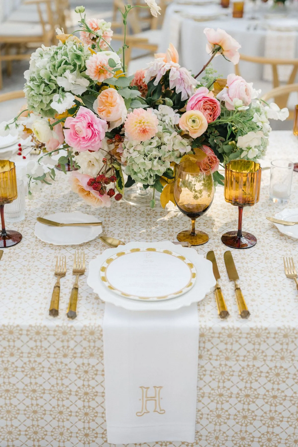 Bridal shower table with pastel floral centerpiece, gold-rimmed plates, and amber glassware.