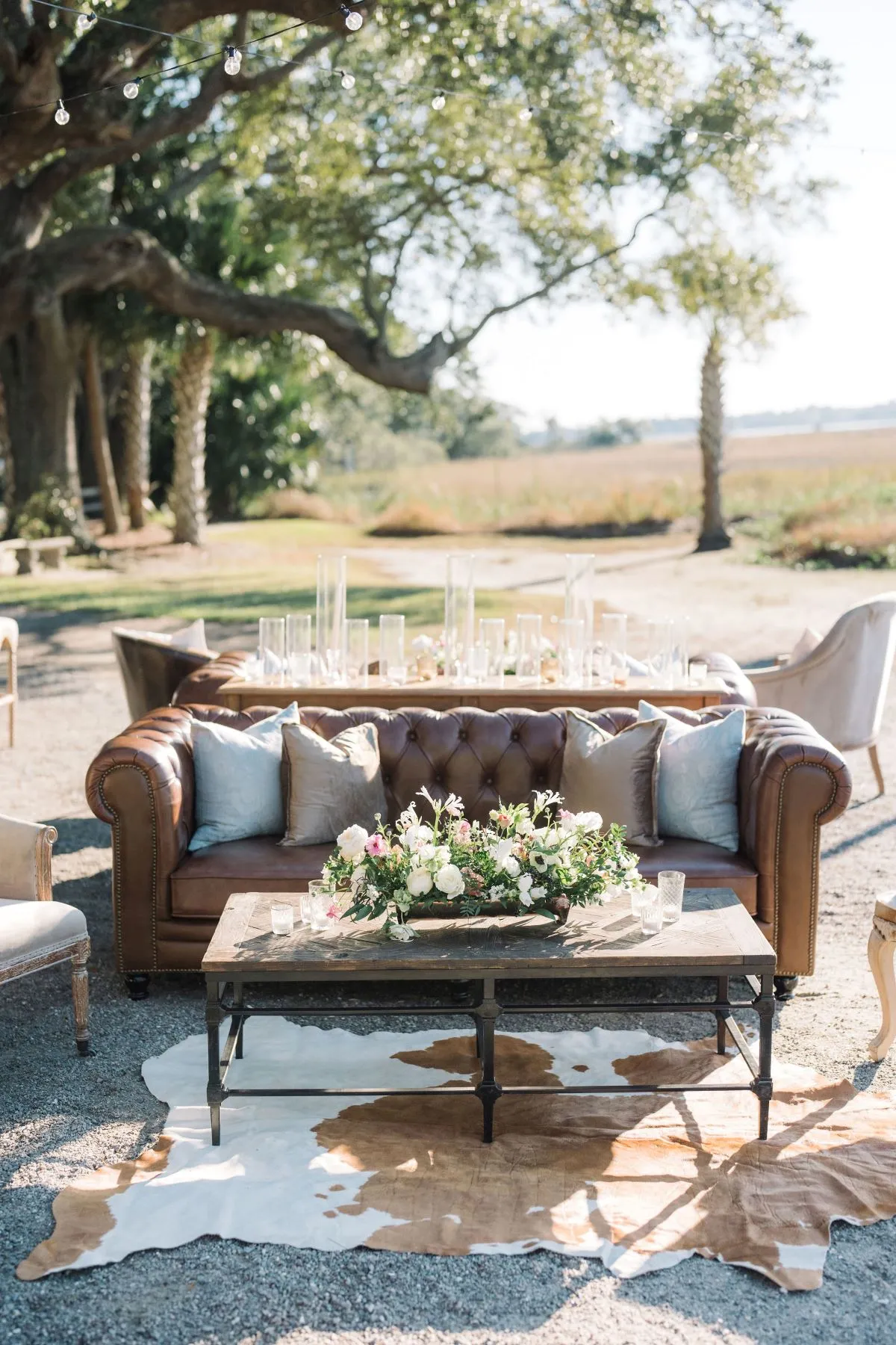 Outdoor lounge setup with leather sofa, coffee table, and floral arrangement.